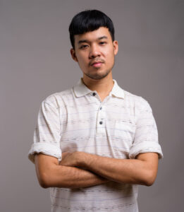 portrait of young asian man against gray backgroun WKTJX7J